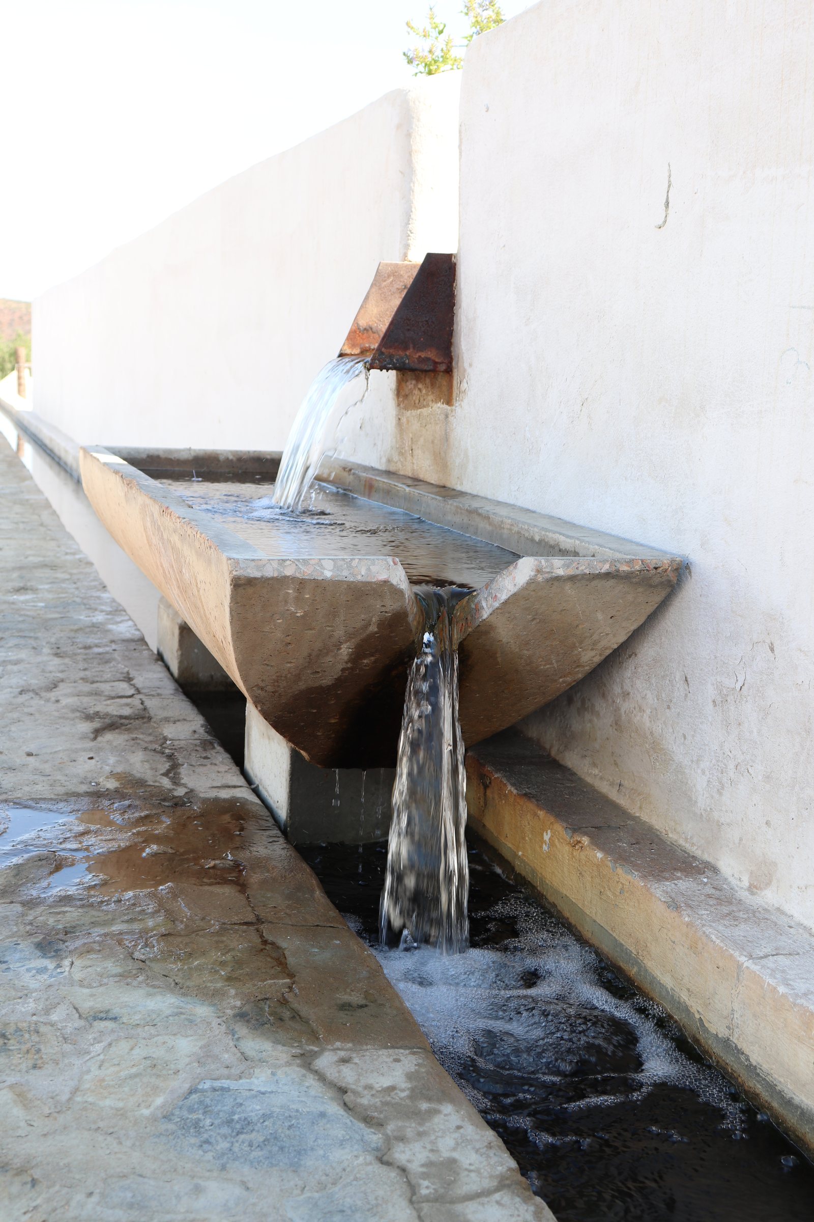 Buffelsdrift — water falling from the steel spout into the repurposed precast trough, then into the leiwatervore
